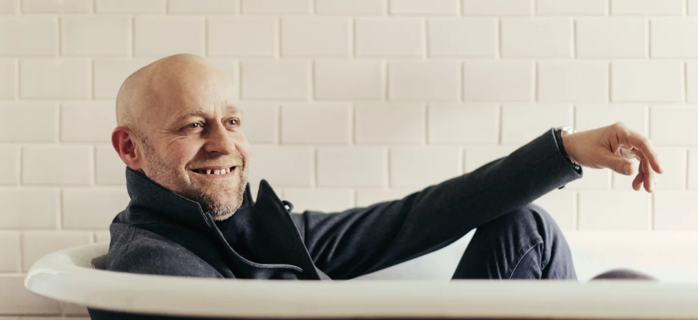 Jürgen Vogel liegt angezogen in der Badewanne